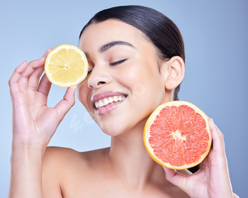 A happy smiling mixed race woman holding a lemon and grapefruit. Hispanic model promoting the skin