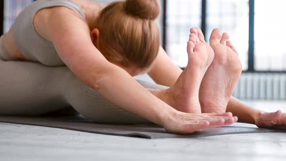 Tranquil barefoot woman yoga trainer in beige sportswear