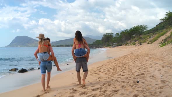 Men carry women on back at beach 