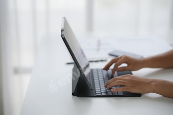 A person typing on a tablet with a keyboard attachment