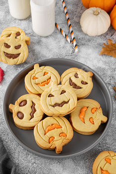 Halloween pumpkin shaped sandwich cookies with sweet cream filling with milk. Jack o lantern cookies