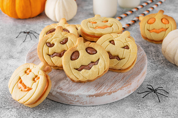 Halloween pumpkin shaped sandwich cookies with sweet cream filling with milk. Jack o lantern cookies