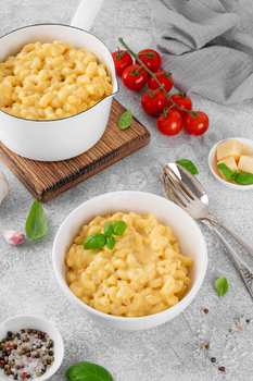 Mac and cheese in a white bowl with fresh basil on top. American cuisine, comfort food. Copy space.