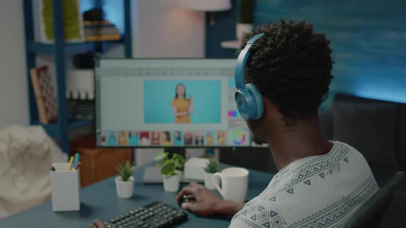 Photographer Retouching Pictures on Computer and Wearing Headphones