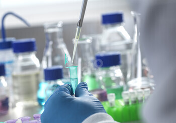 Scientist pipetting liquid into a test tube in a lab.