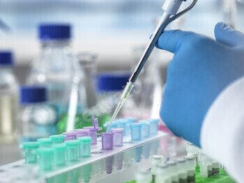 Scientist pipetting liquid into test tubes in a lab.