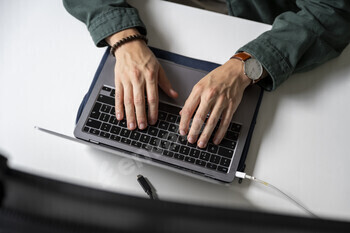 Hands typing on a laptop keyboard.