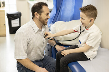 Child plays doctor with adult doctor in a clinic setting