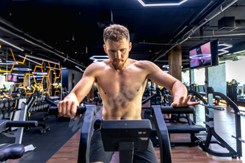 Athlete doing exercises on an air bike exercise bike close-up.