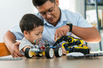 A boy are learning to build robot toys with their dad in the living room. Robot model