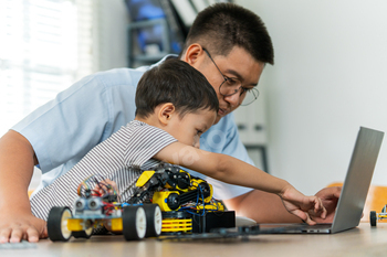 A boy are learning to build robot toys with their dad in the living room. Robot model