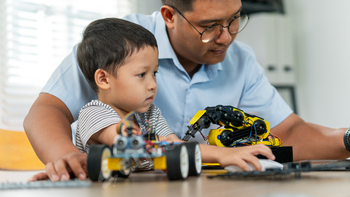 A boy are learning to build robot toys with their dad in the living room. Robot model