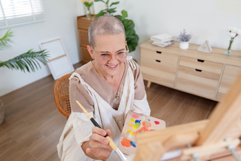 Senior woman painting on canvas at home, Elderly woman painting on a canvas, Happy retirement