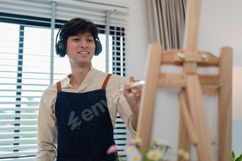 Young Artist Painting on Canvas with Headphones in Modern Studio