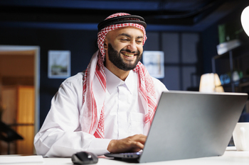 Muslim man checking email on laptop