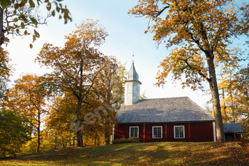 Neat wooden church in the autumn forest. Autumn church landscape. Church in the open air.