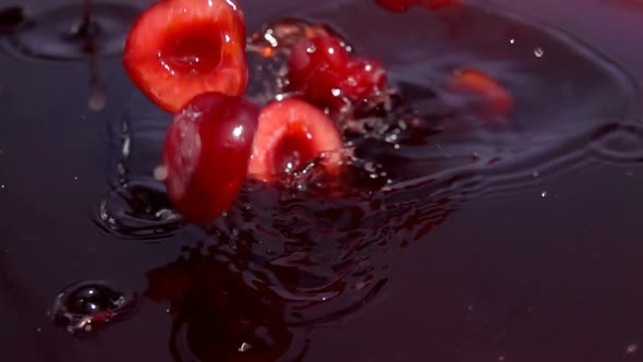 Ripe Cherry Halves are Falling Into Juice with Beautiful Splashes