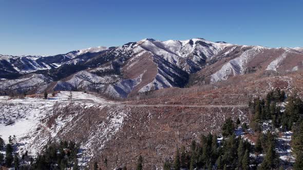 Drone shot pushing overtop of a mountain road with a mountain in distance