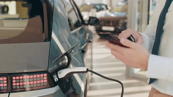 Unrecognizable Businessman Plugging Electric Car From Charging Station