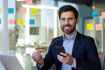 Businessman using smartphone and credit card in office