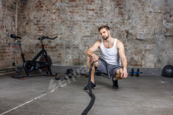 A man engaged in fitness and sports trains with ropes in the cross fit gym.Fitness,workouts concept