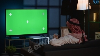 Man plays videogames on green screen TV