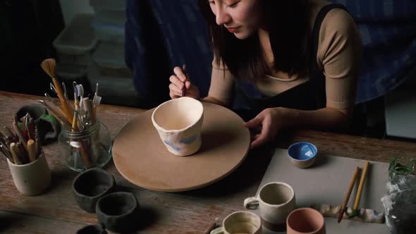 A female ceramicist is creating a new pottery in the workshop. Asian woman is enjoying pottery work.