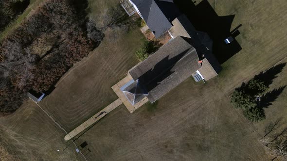 Top-down aerial view in 4k of a person walking along narrow paved path and going to church. 90 degre