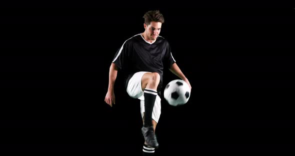 Athlete practicing soccer against black background