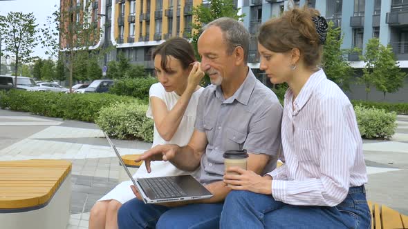 Senior Businessman Mentor or Coach is Teaching an Interns Pointing at Laptop Screen Helping New