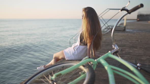 Young Attractive Woman with Long Hair is Having a Good Time on Sea at Sunset or Sunrise