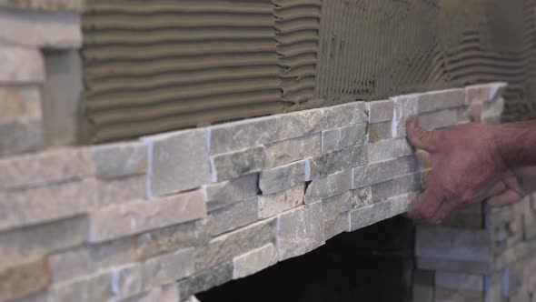 Male Worker Hands Setting Stacked Stone Tiles for a Fireplace