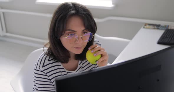 Happy millennial professional designer portrait in eyeglasses with apple