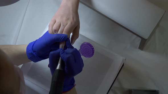 manicure master using a machine to clean the nails