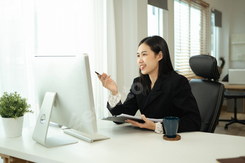 Beautiful young businesswoman analyzing financial data at desktop computer