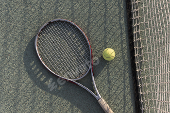 tennis racquet and ball lie on a clay tennis court, ready for a game