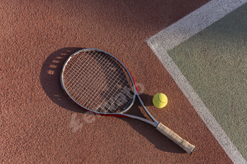 tennis racquet and ball lie on a clay tennis court, ready for a game