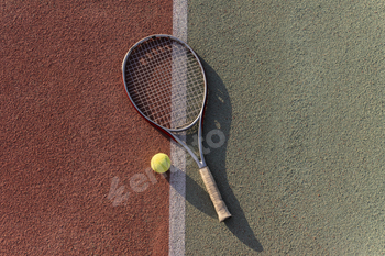 tennis racquet and ball lie on a clay tennis court, ready for a game