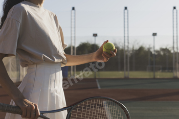 a female tennis player holds a tennis ball in her right hand while standing on a tennis court.