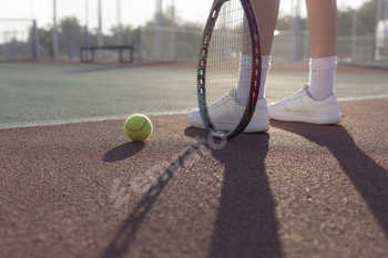 the womans legs holding a tennis racket on a clay tennis court