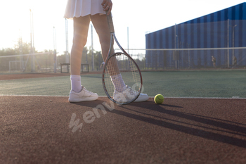 the womans legs holding a tennis racket on a clay tennis court