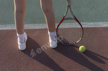 the womans legs holding a tennis racket on a clay tennis court