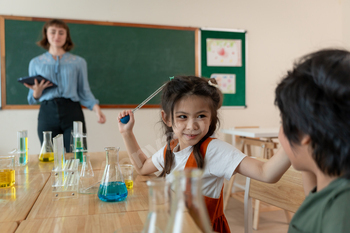 Adorable student learn with teacher in classroom at elementary school.