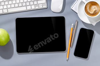 Blank screen smartphone and tablet on a desk