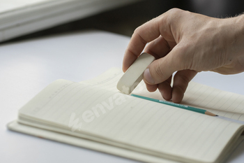 a student holding the rubber and erasing errors in notebook