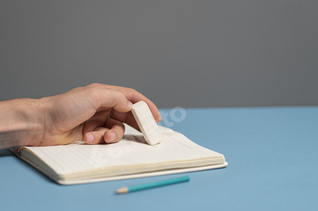 a student holding the rubber and erasing errors in notebook