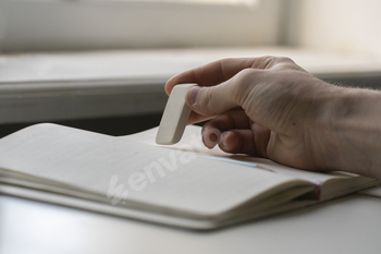 a student holding the rubber and erasing errors in notebook