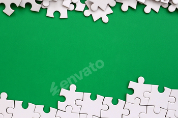 Fragment of a folded white jigsaw puzzle and a pile of uncombed puzzle elements