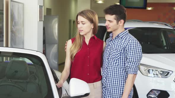 Loving Couple Examining a New Convertible for Sale at the Dealership