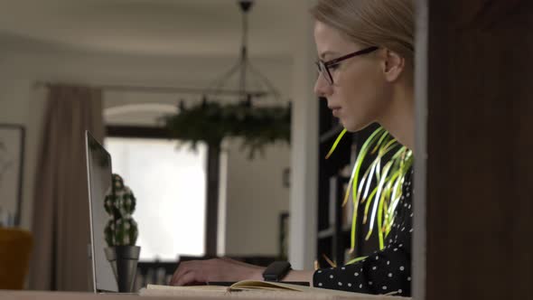 woman with glasses working on her laptop in her home office